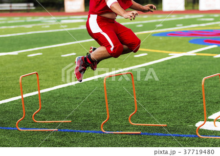 Football player jumping over orange hurdles, 37719480