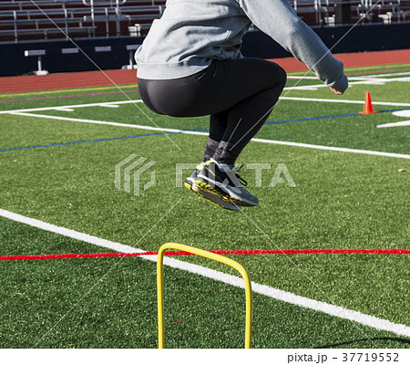 Side view of an athlete jumping over hurdles 37719552