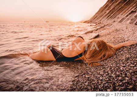 Beautiful woman in black swimwear relaxing on sea Beautiful woman in black swimwear relaxing on sea 37735053