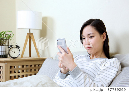 寝室でスマートフォンを見る女性 37739269
