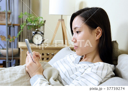 寝室でスマートフォンを見る女性 寝室でスマートフォンを見る女性 37739274
