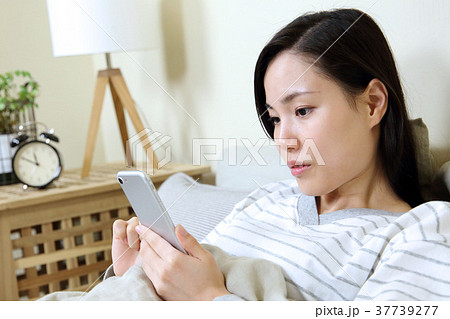 寝室でスマートフォンを見る女性 37739277