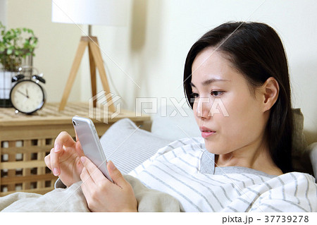 寝室でスマートフォンを見る女性 37739278