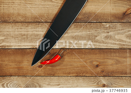 Red pepper with a knife on a wooden background 37746935