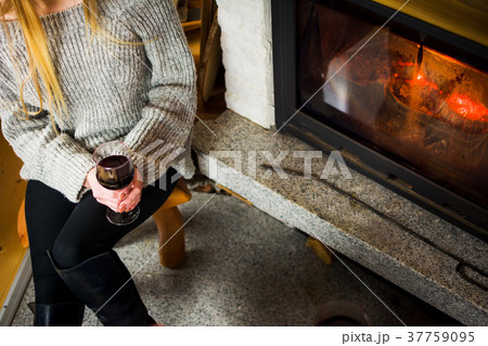 Girl with wine glass by the fireplace 37759095