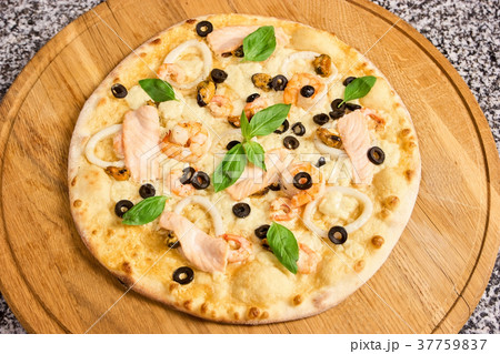 Pizza with seafood, olives and basil leaves. Pizza with seafood, olives and basil leaves. 37759837