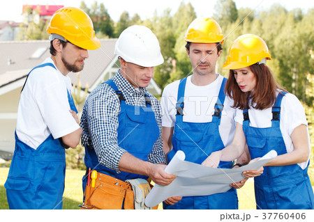 Builders in hardhats with blueprint 37760406