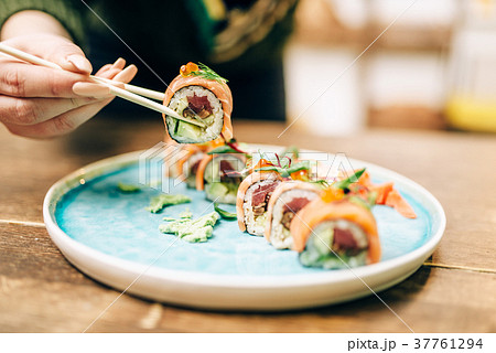 Male person eats sushi rolls with chopsticks 37761294