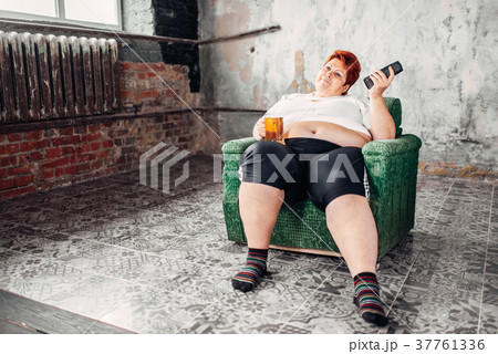 Overweight woman drinks beer, high calorie food 37761336