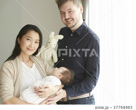 国際結婚 赤ちゃんを抱く夫婦 ポートレートの写真素材