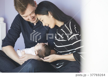 子供部屋で赤ちゃんを慈しむ両親 子供部屋で赤ちゃんを慈しむ両親 37769264