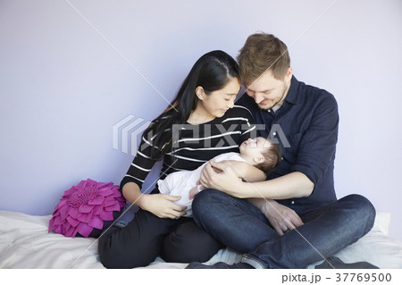 子供部屋で赤ちゃんを慈しむ両親 37769500