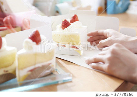 ケーキ屋さんで箱詰めする手の写真素材