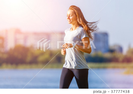 Young smiling woman running in park in the morning 37777438
