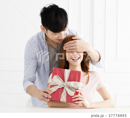 man surprises his girlfriend with present at homeの写真素材