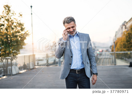 Mature businessman with smartphone in a city. 37780971