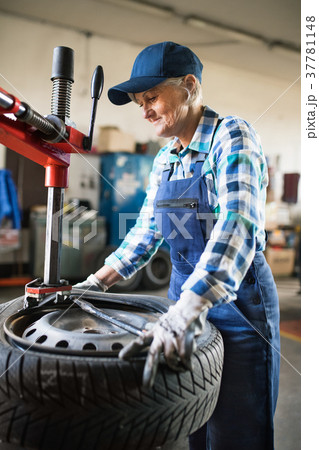 Senior female mechanic repairing a car in a garage Senior female mechanic repairing a car in a garage 37781148