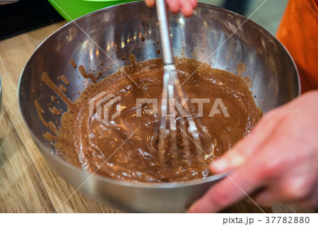 Hands mix chocolate dough with whisk Hands mix chocolate dough with whisk 37782880