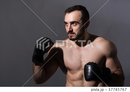 Portrait of a young muscular man in boxing gloves  37785767