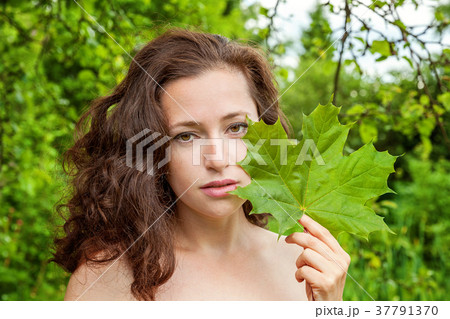 Girl with the leaf in her hand in a park 37791370