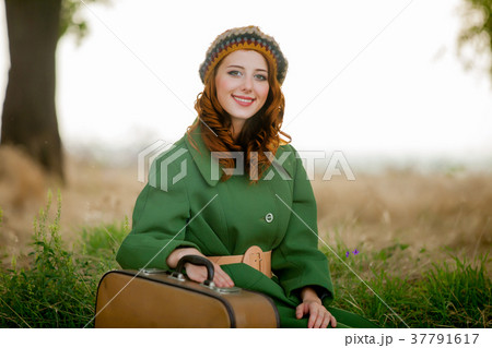 portrait of adult girl in green coat with suitcase 37791617