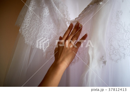 Female hand touches wedding dress close up Female hand touches wedding dress close up 37812413