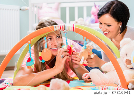 Women furnishing baby room preparing play bar for Women furnishing baby room preparing play bar for 37816941