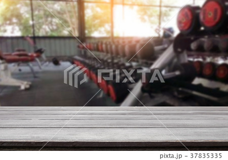Wooden table on blurred background of fitness gym interior of mo Wooden table on blurred background of fitness gym interior of mo 37835335