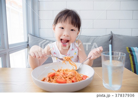 Little girl using fork eating spaghetti by herself 37837936