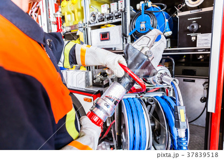 Fire fighter checking hydraulic cutter at fire 37839518
