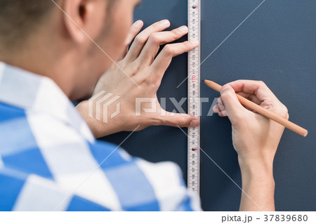 Young handyman sizing with yardstick and pencil 37839680