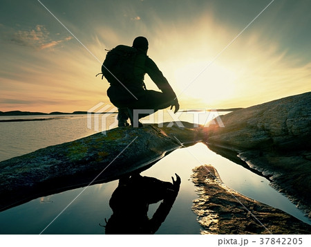 Man hiker sits alone on coast and enjoy sunset. Man hiker sits alone on coast and enjoy sunset. 37842205