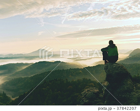 Hiker man take a rest on mountain peak. Man sit  37842207