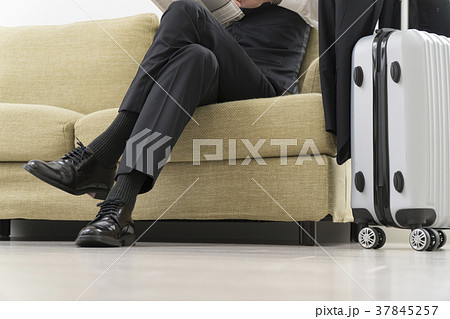 ソファで新聞を読むビジネスマンの写真素材