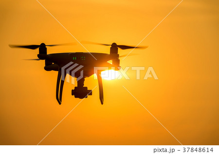 Silhouette drone with camera flying at sunset. Silhouette drone with camera flying at sunset. 37848614
