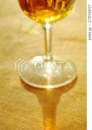 blurry glass of brandy on wooden table 37850857