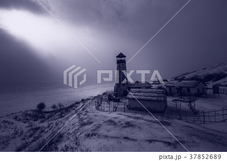 Old wooden lighthouse in night at edge of frozen 37852689