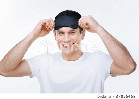 Happy joyful man putting on a sleeping mask Happy joyful man putting on a sleeping mask 37856468
