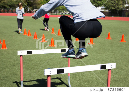 Female athlete bounds over a hurdle 37856604