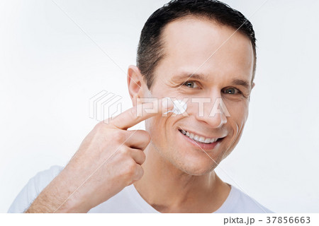 Positive nice man using facial cream 37856663