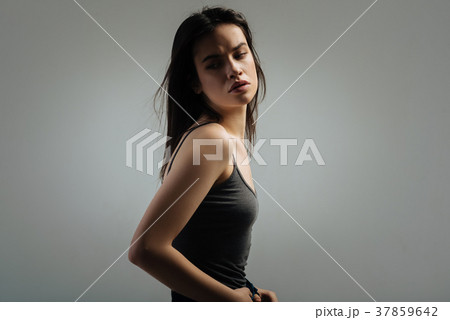 Unsmiling young woman looking over her shoulder Unsmiling young woman looking over her shoulder 37859642
