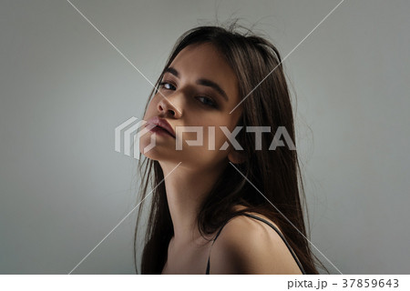 Humourless young woman looking over her shoulder Humourless young woman looking over her shoulder 37859643
