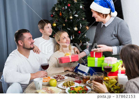 Elderly woman giving Christmas presents to family 37862153