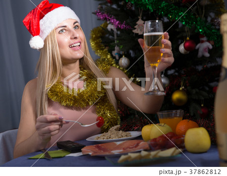 Young female is watching TV and sitting with champagne in New Year night Young female is watching TV and sitting with champagne in New Year night 37862812