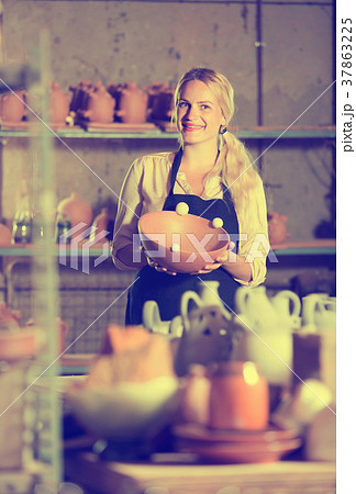 Adult glad woman potter carrying ceramic vessels 37863225