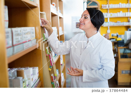 Woman in white coat promoting health supplements in drugstore Woman in white coat promoting health supplements in drugstore 37864484