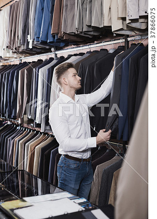 Young man choosing new suit in men’s cloths store Young man choosing new suit in men’s cloths store 37866075