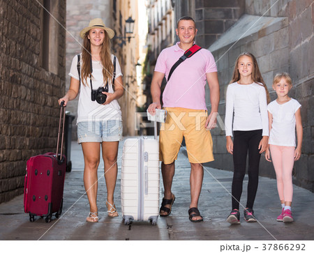 Glad family of tourists walking with suitcases 37866292