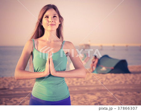 Female 20-25 years old is standing and practicing meditation in blue T-shirt Female 20-25 years old is standing and practicing meditation in blue T-shirt 37866307