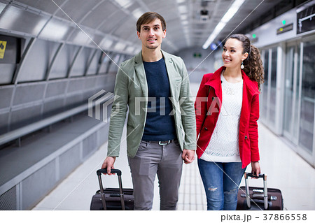 Portrait of couple with wheeled trollers at subway platform 37866558